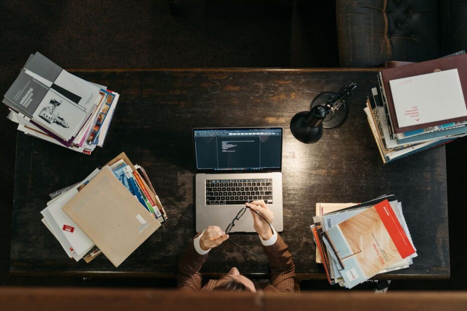 Studente seduto a una scrivania di legno con pile di libri, sessione di studio